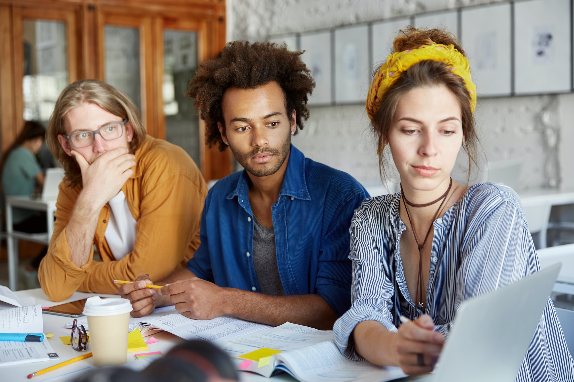 Portrait of three collegues or partners working together at coworking space, discussing business ide